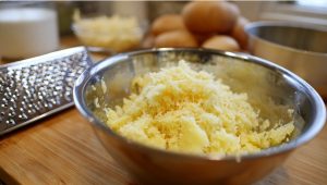 Терта картопля у металевій мисці — підготовка маси для дерунів.