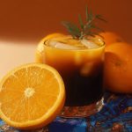 Капуоранж у склянці з льодом поруч із половинкою апельсина