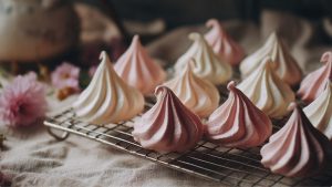 Домашнє безе рожевого і білого кольору на решітці після випікання.