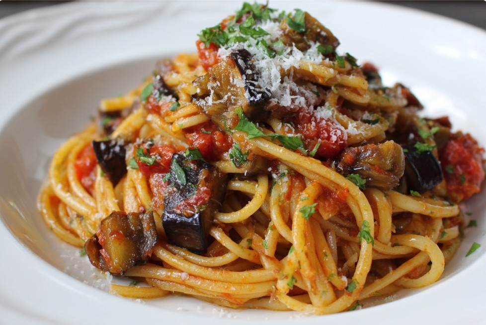 Паста з баклажанами та томатами, посипана сиром.