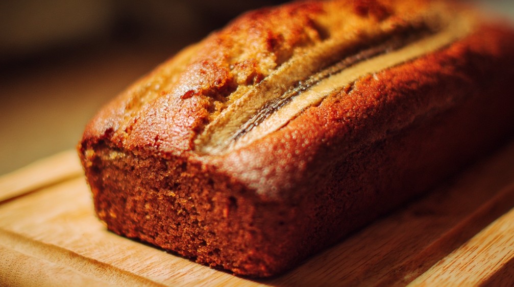 Банановий хліб, поданий цілим буханцем на дерев’яній дошці