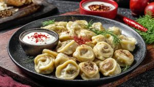 Готові пельмені вийміть з каструлі за допомогою шумівки і подавайте гарячими зі сметаною.