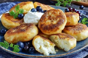 Сирники без яєць зі сметаною і ягодами на столі