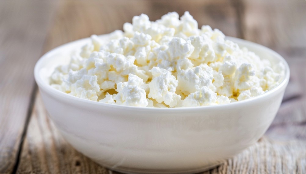 Магазинний кисломолочний сир у білій мисці з рівною текстурою