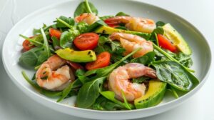 Розкладіть салат на охолоджені тарілки, зверху додайте авокадо й теплі креветки